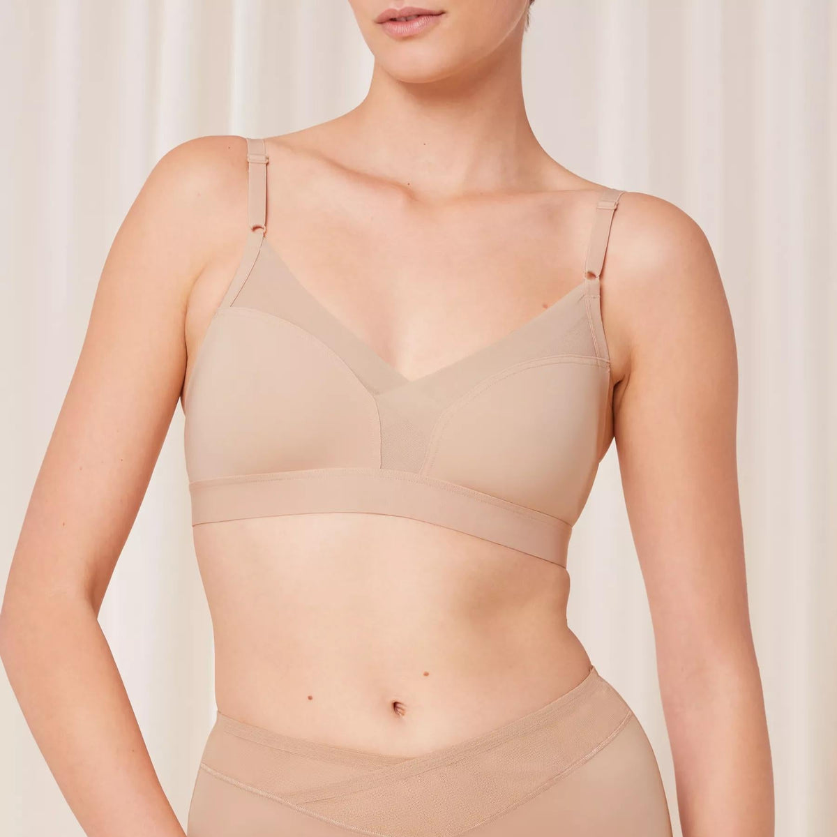 Kūno spalvos „bralette“ tipo liemenėlė be lankelių ir pakietinimo Triumph Shape Smart N iš priekio ant modelio kūno