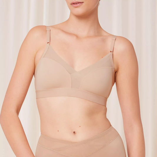 Kūno spalvos „bralette“ tipo liemenėlė be lankelių ir pakietinimo Triumph Shape Smart N iš priekio ant modelio kūno